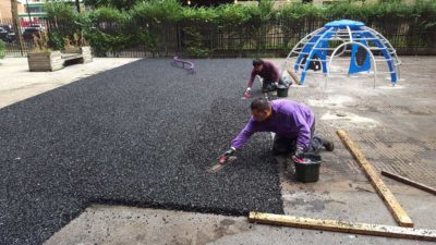 A work team replacing rubber tiles with poured rubber playground surfacing