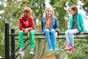 Three children sitting on playground equipment