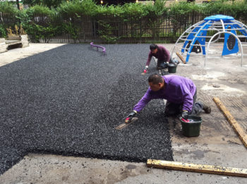 A work team replacing rubber tiles with poured rubber playground surfacing